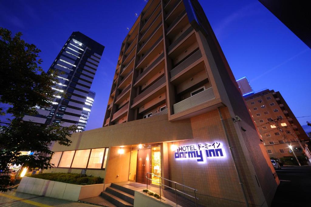 a building with a sign on the side of it at Dormy Inn Sendai Station Natural Hot Springs in Sendai