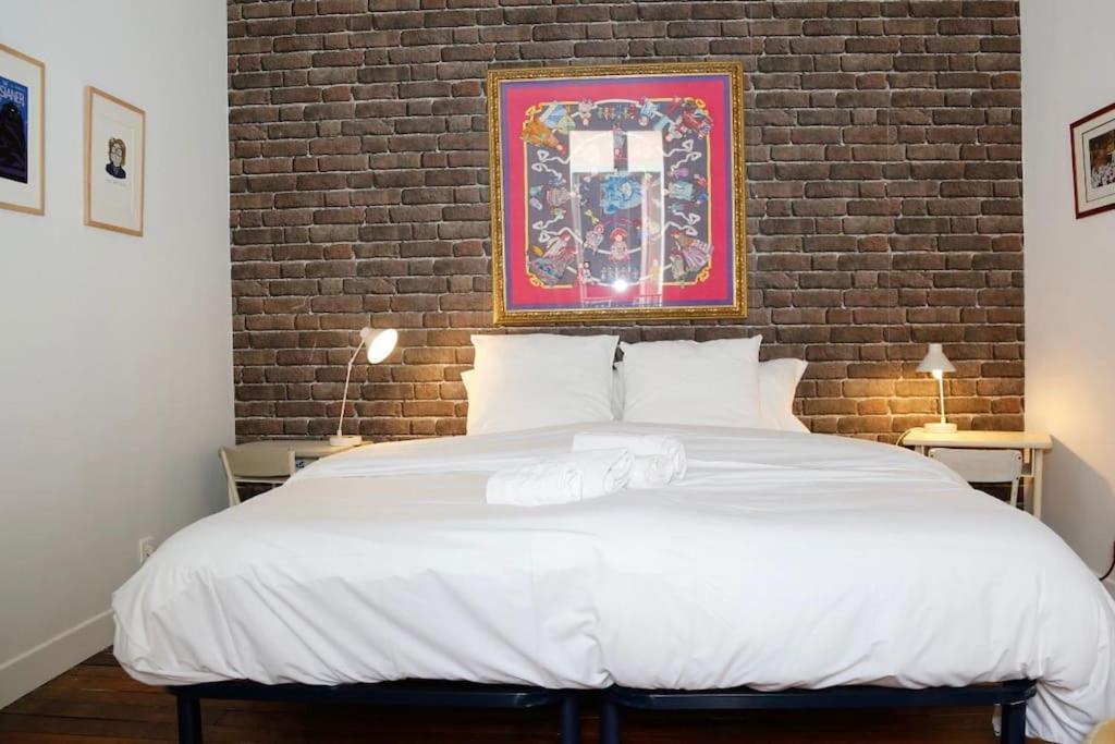 ein Schlafzimmer mit einem großen weißen Bett mit Ziegelwand in der Unterkunft Jolie maison de ville à 5 minutes de Paris pour 5 voyageurs parking inclus in Clichy