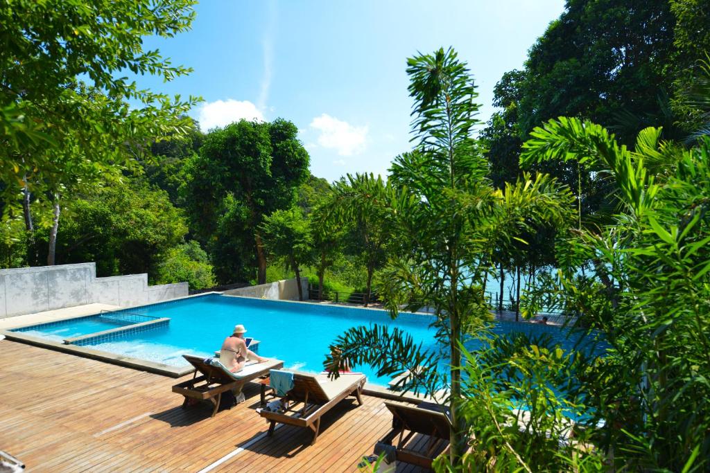 eine Person, die auf einem Deck neben einem Pool sitzt in der Unterkunft Railay Great View Resort in Railay Beach