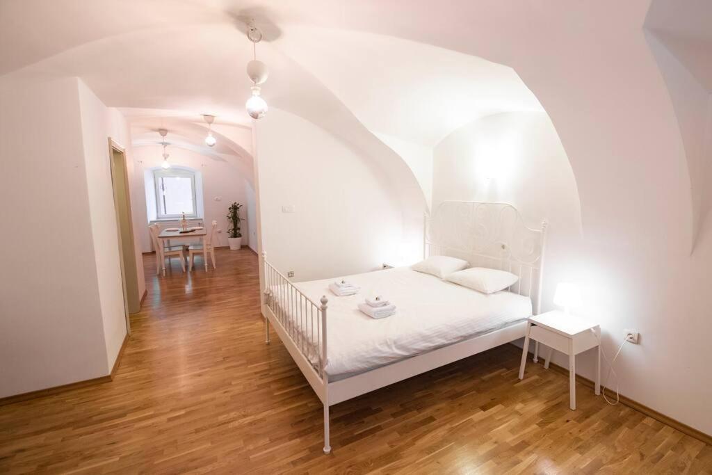 a white bedroom with a bed in an archway at Dragon's Cave in Ljubljana