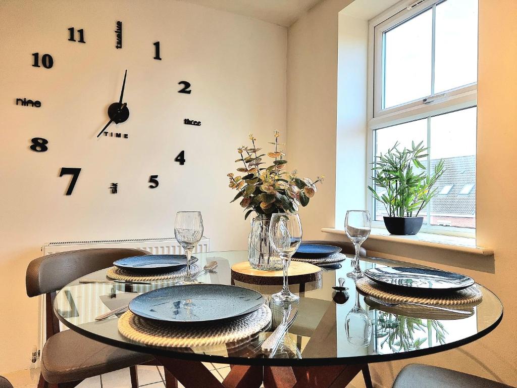 a dining room with a table and a clock on the wall at Large House with Free Parking and Long Stay Offers in Leicester