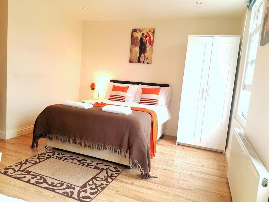 um quarto com uma cama com almofadas laranja em Comfortable Studio flat near Central London em Londres