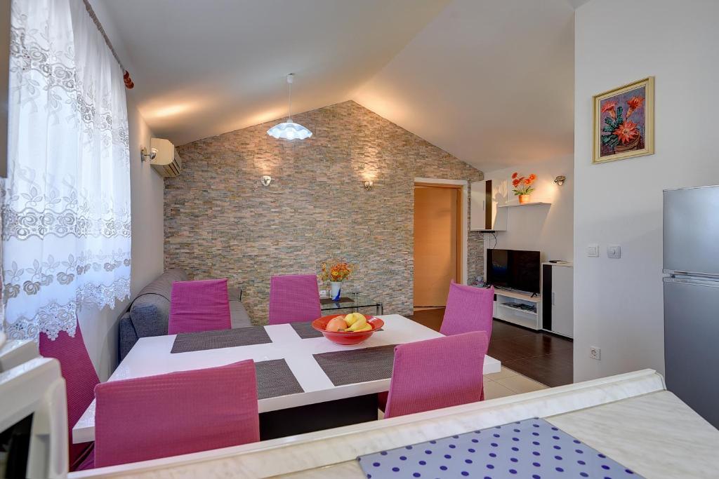 a kitchen and dining room with a table and purple chairs at House Jasminka in Medulin