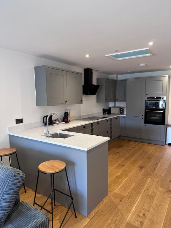 uma cozinha com armários brancos e uma ilha de cozinha com bancos em House situated on River Itchen em Winchester