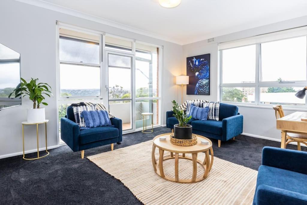 a living room with blue chairs and a table at Mosman Views, 2bed, Parking, 15min Walk to Beach in Sydney