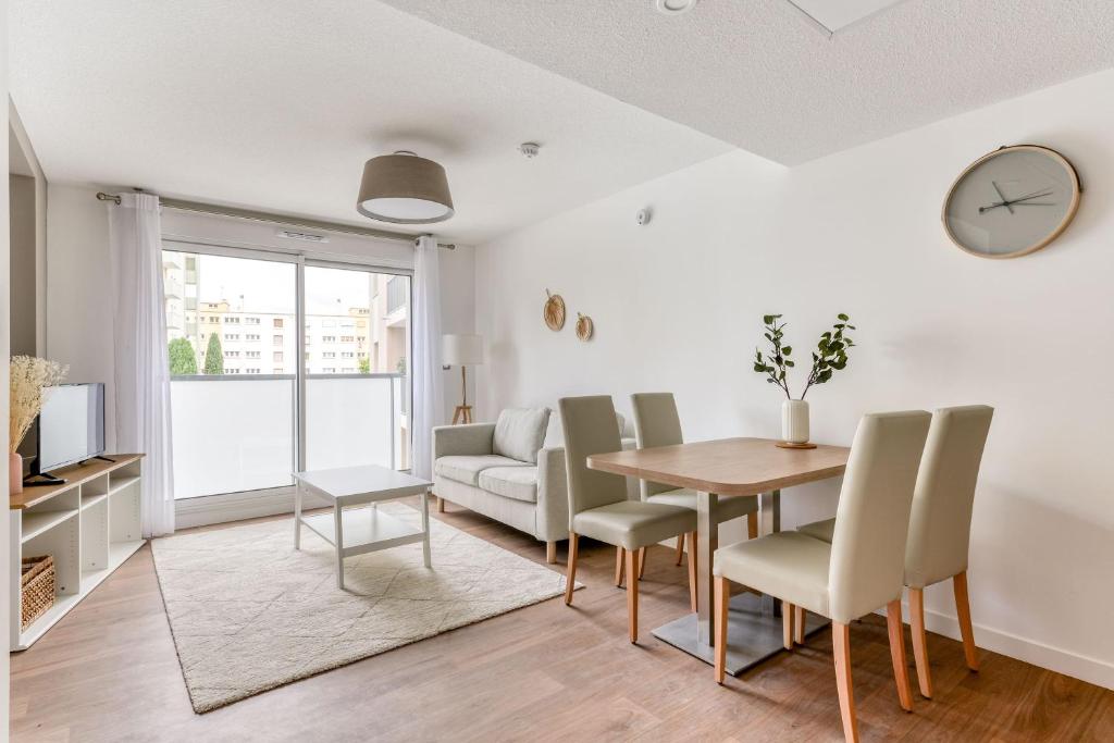 uma sala de estar com mesa e cadeiras e um relógio em OVELIA Montpellier - Les Balcons de Montcalm em Montpellier