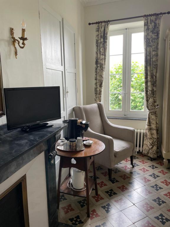 een woonkamer met een televisie, een stoel en een tafel bij Le Chai de Marguerite in Peyriac-Minervois