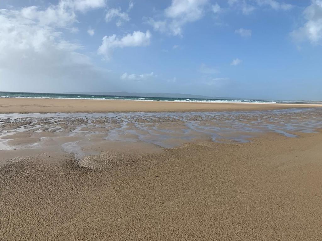 a sandy beach with a body of water at Kerry Coastal Hideaway in Fenit