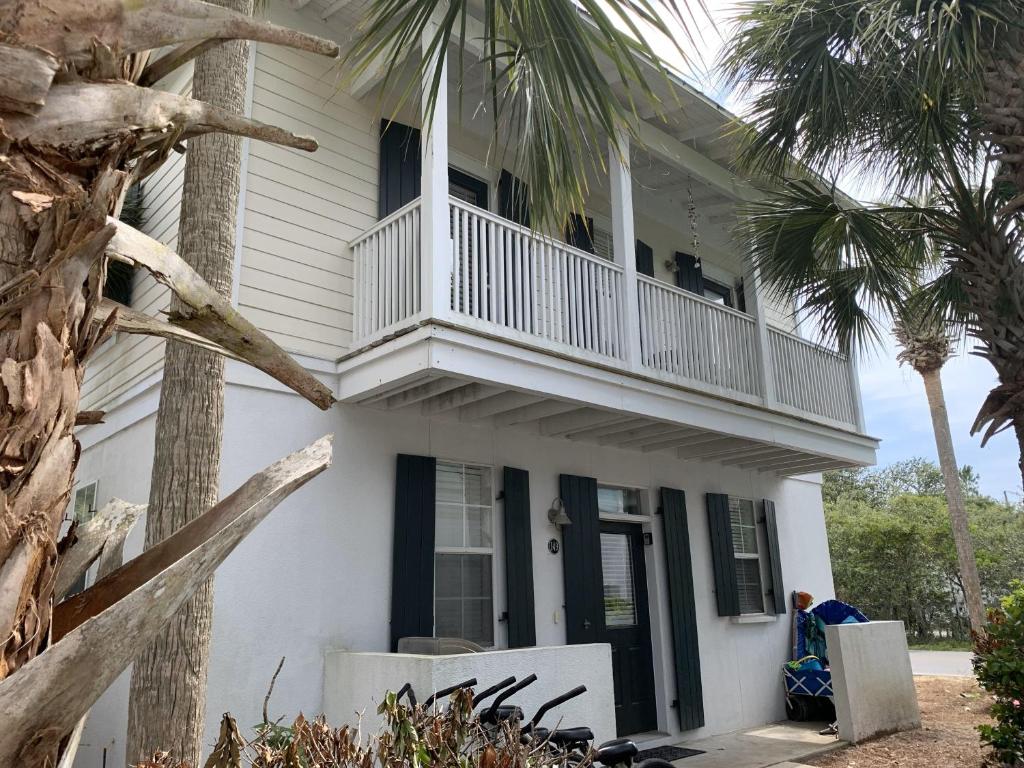 a white house with a balcony and palm trees at Bungalows At Seagrove 149 - Three Little Birds Bungalow in Seagrove Beach