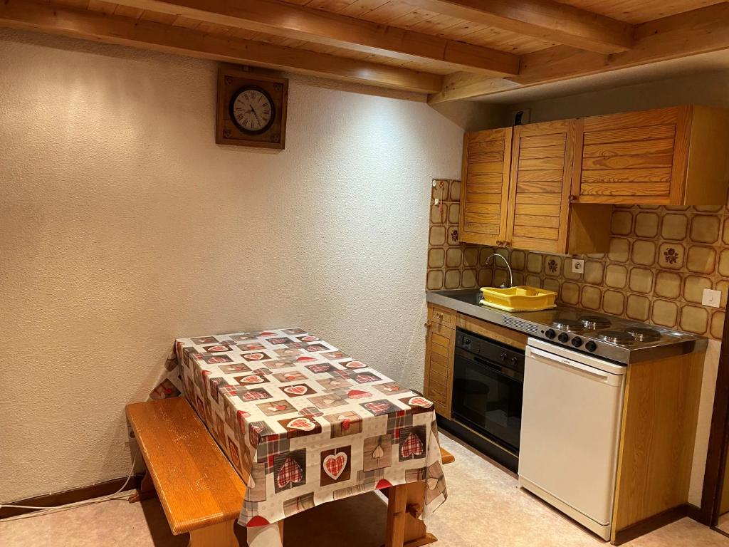 une cuisine avec une table et une horloge au mur dans l'établissement Duplex au centre de SAMOENS - 6 couchages, à Samoëns