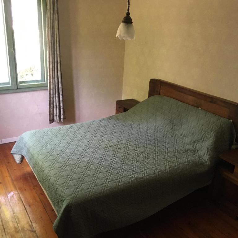 a bedroom with a bed with a green comforter at "Maroli House" in Vrŭv
