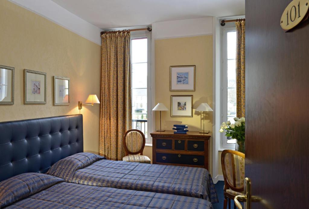 Un dormitorio con una cama azul y una ventana en Churchill Hotel Bayeux Centre, en Bayeux