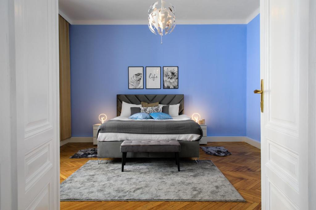ein blaues Schlafzimmer mit einem Bett und einem Kronleuchter in der Unterkunft Infinity Homes - Stylish 3-Bedroom Haven in the Heart of Vienna! in Wien