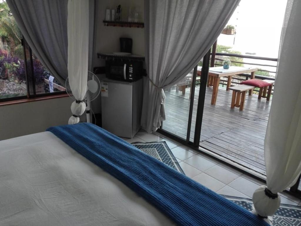 a bedroom with a bed and a view of a patio at Yacht Lake Lodge in Hartbeespoort