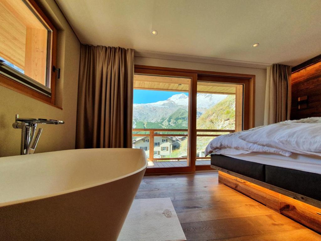 a bathroom with a tub and a bed and a window at Luxury Chalet Engedi in Saas-Fee