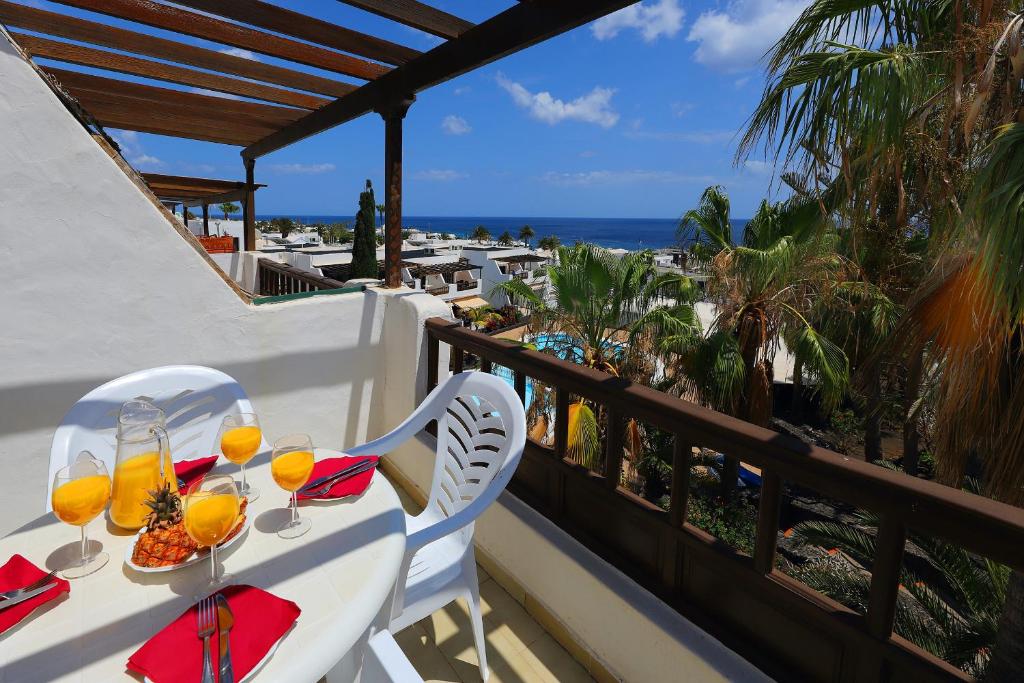 a balcony with a table with glasses of orange juice at Los Helechos A1, central 2 bed PDC in Puerto del Carmen