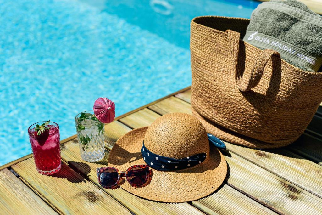 um chapéu e óculos de sol sentados numa mesa ao lado de uma piscina em Oliva Holiday Homes em Dhiyeliótika