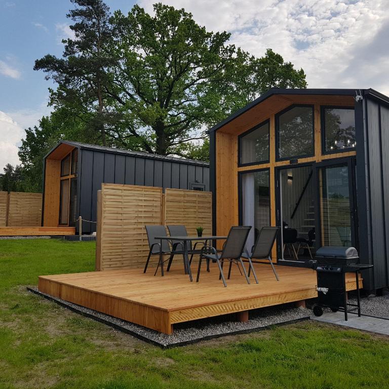 a tiny house with a table and chairs on a deck at DOMKI POD DĘBAMI , Radawa in Radawa