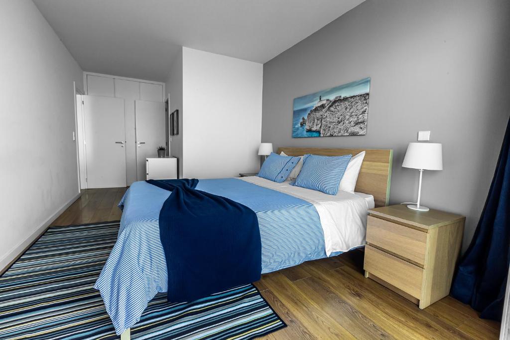 a bedroom with a blue and white bed and a rug at Xenon Urban Apartments in Maputo