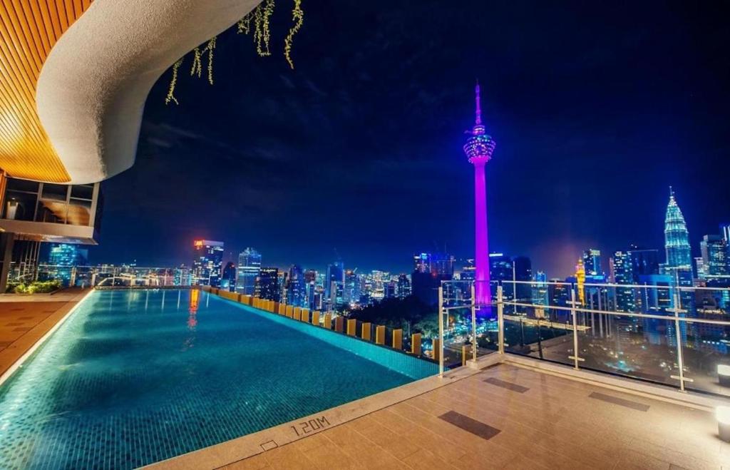 una piscina en la azotea con vistas a la ciudad por la noche en Ceylonz Leisure Suites KLCC, en Kuala Lumpur