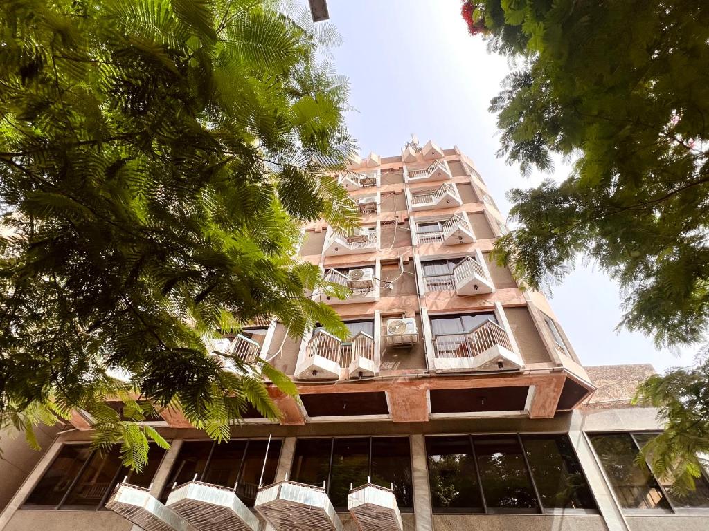 un edificio alto con balcones y árboles en Santana Hotel Cairo, en El Cairo