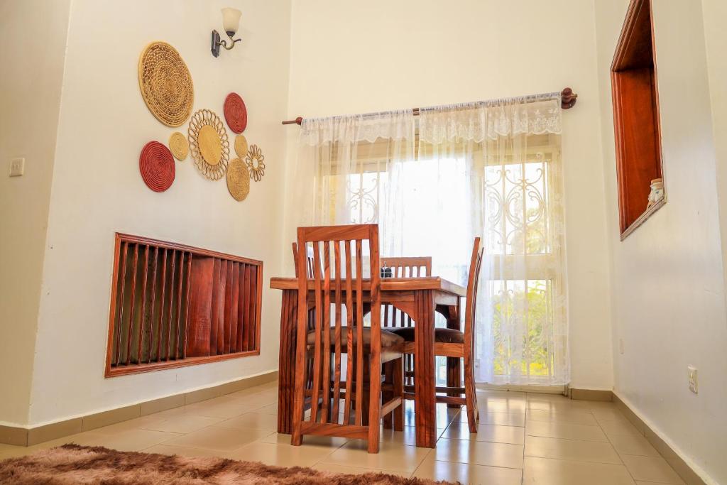 a dining room with a table and chairs and a window at Stee's Cottages in Mukono