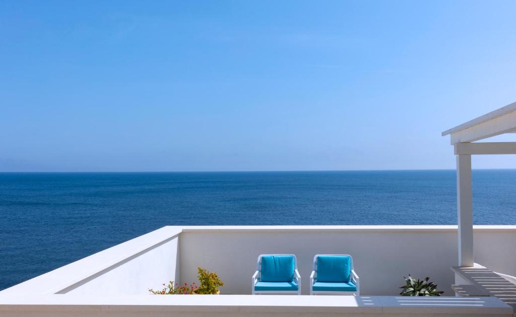 2 sillas azules sentadas en un balcón con vistas al océano en Le Conchiglie, en Marettimo