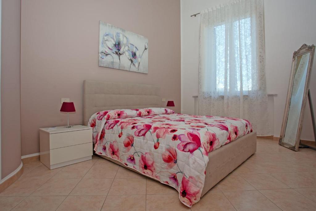 a bedroom with a bed with a red floral bedspread at Casa Dafne in Livorno