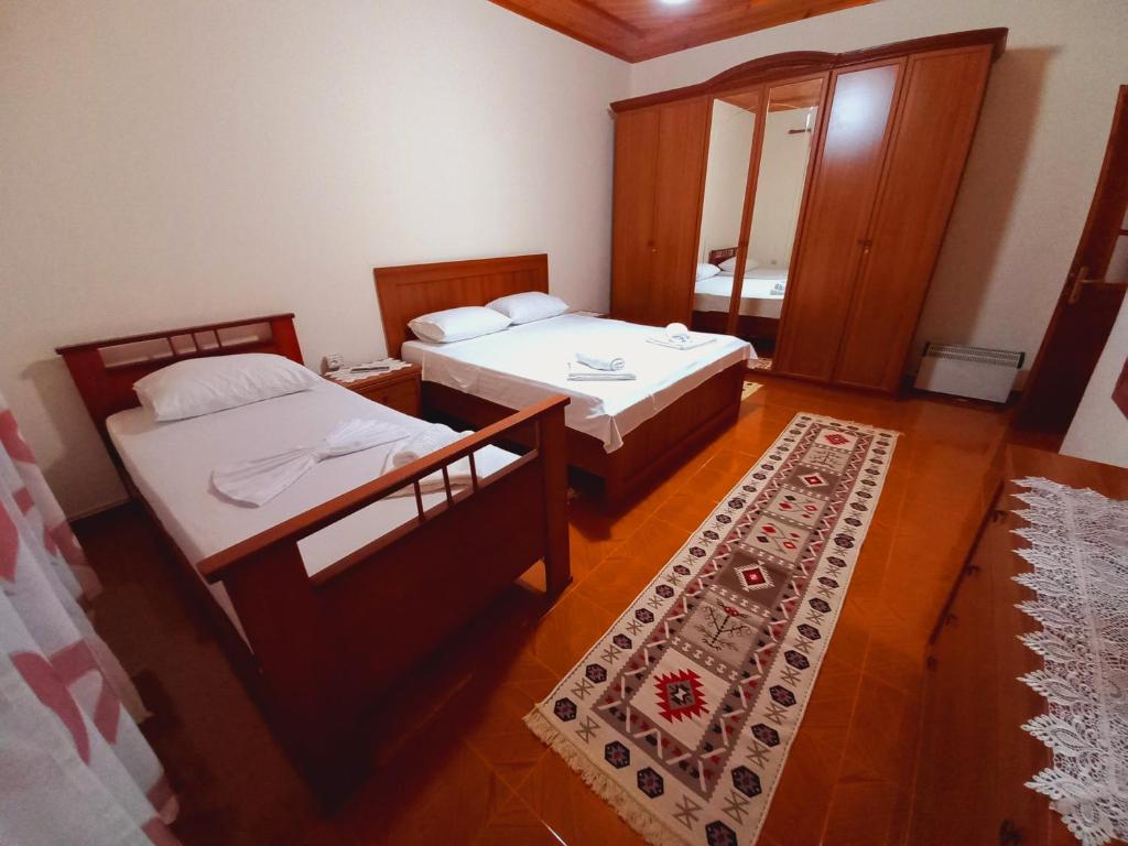 two beds in a small room with a rug at Sokolli Guest House in Gjirokastër