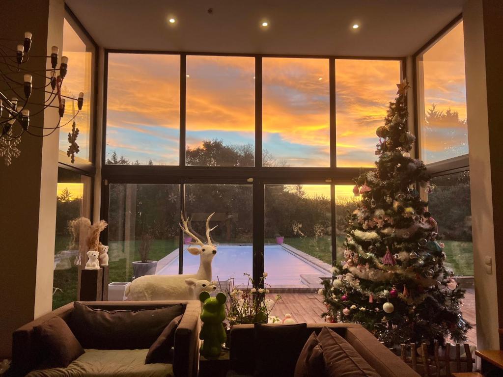 ein Wohnzimmer mit einem Weihnachtsbaum vor einem Fenster in der Unterkunft Maison Proche de Le Mans Classique in Changé