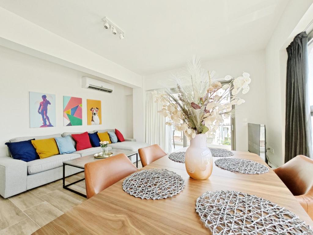 una sala de estar con una mesa con un jarrón de flores en Costa Alimos by Verde Apartments en Atenas