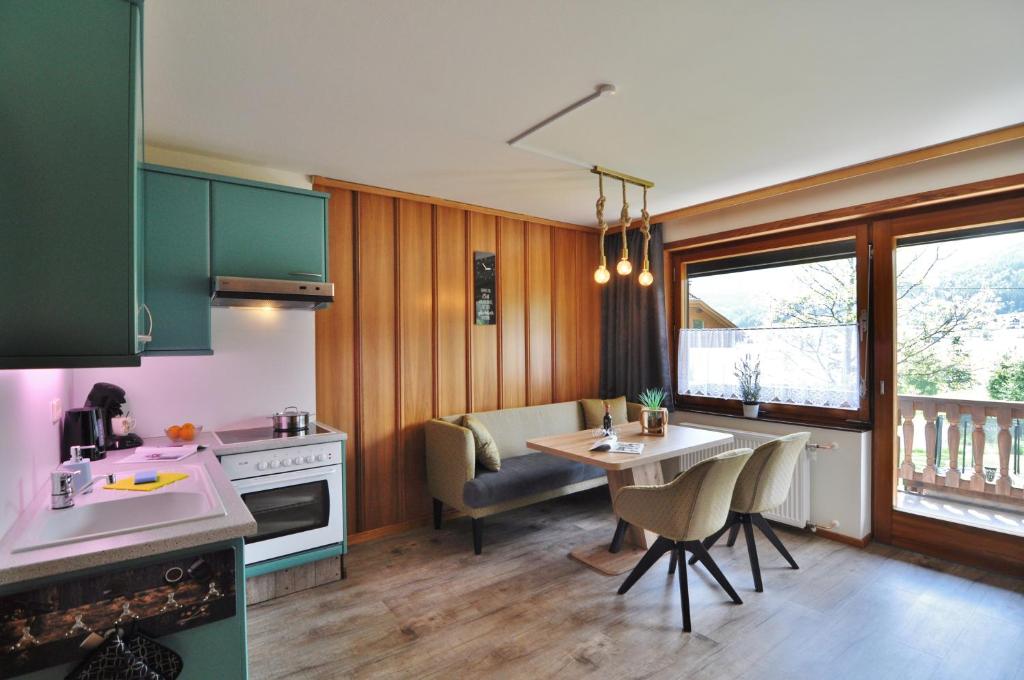 una cucina con armadi verdi e un tavolo con sedie di Pension & Apartments Weissbriach a Weissbriach