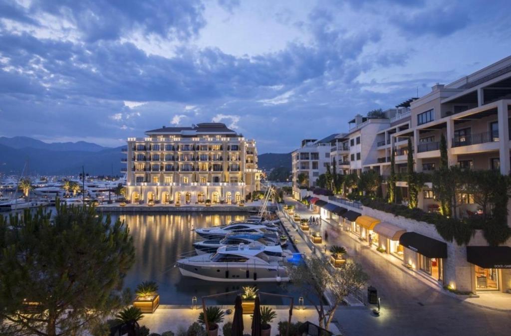 un grand bâtiment avec des bateaux dans un port de plaisance la nuit dans l'établissement Porto Montenegro - Residence Tara, à Tivat