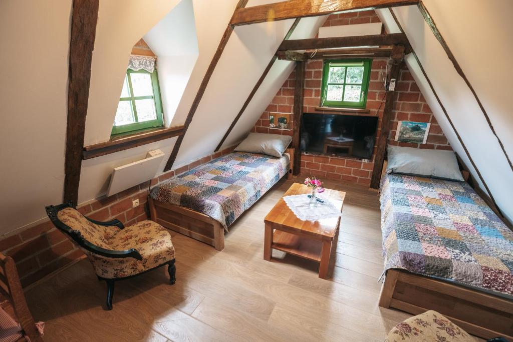 Cette chambre mansardée comprend deux lits et une table. dans l'établissement APARTMANI Etno kuća pod Okićem, à Samobor