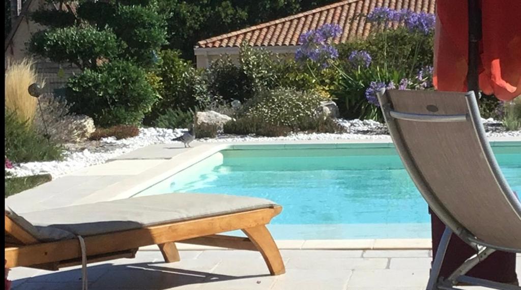 a swimming pool with a chair next to a swimming pool at Chambre indépendante avec piscine in Jarnac