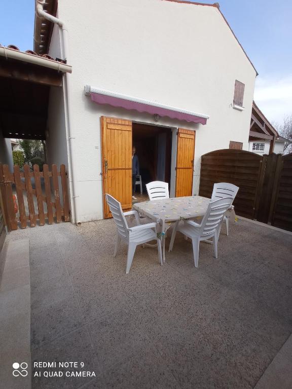 une table et des chaises devant une maison blanche dans l'établissement Maison à 600 m de la plage, à Saint-Georges-de-Didonne