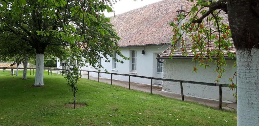 un bâtiment blanc avec une clôture à côté d'une cour dans l'établissement Domaine de la Panetière - Appartement Longère, à Autouillet