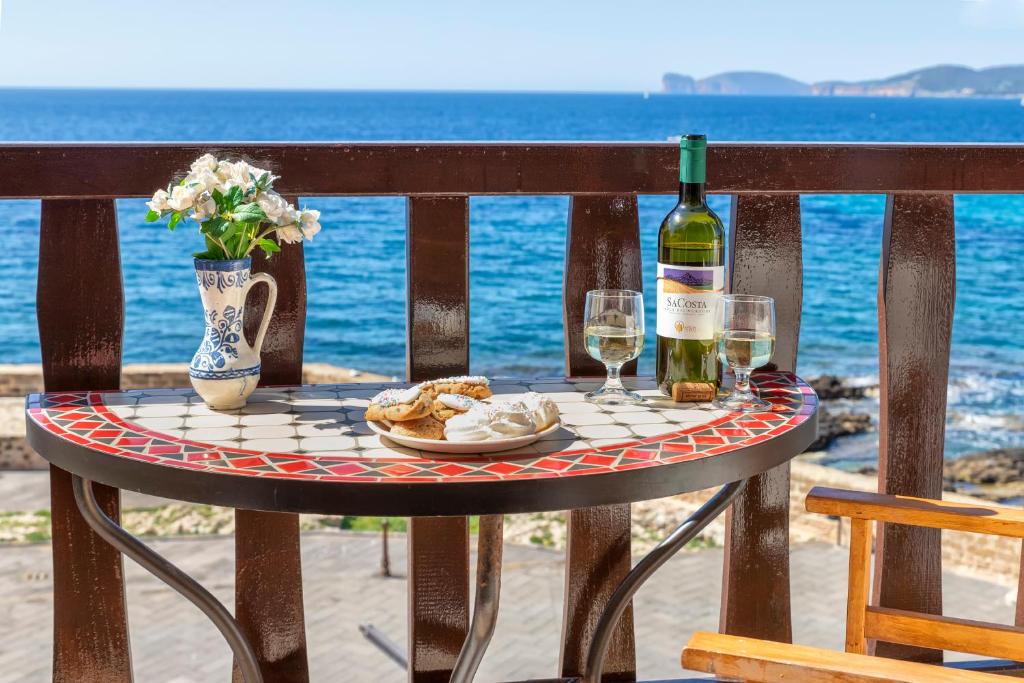 a table with a bottle of wine and two glasses at Alguerhome Casa Blu sea view in Alghero