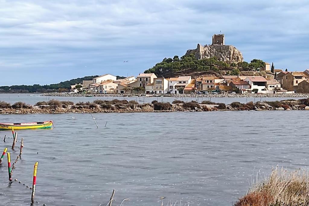 un petit bateau dans un plan d'eau avec une île dans l'établissement Petit appart sympa clim piscine balcon, à Gruissan