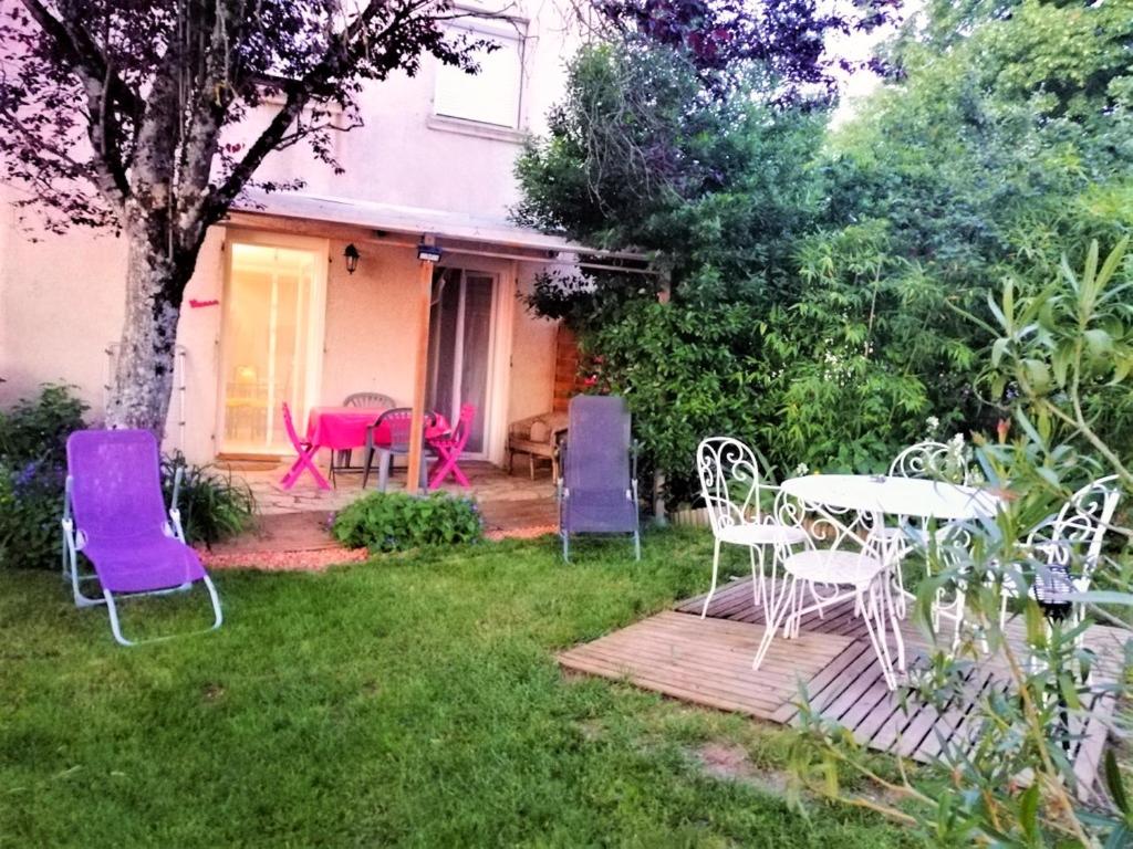 un groupe de chaises et de tables dans une cour dans l'établissement Appartement cosy à Villeneuve avec jardin privé, à Villeneuve-dʼAveyron