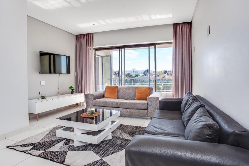 a living room with a couch and a table at Urban Oasis Apartments at One Hyde Park in Johannesburg