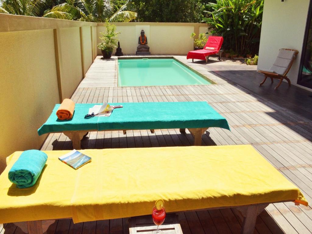 un patio trasero con una piscina con una mesa y un banco en Happy Days Guest House en Le Morne