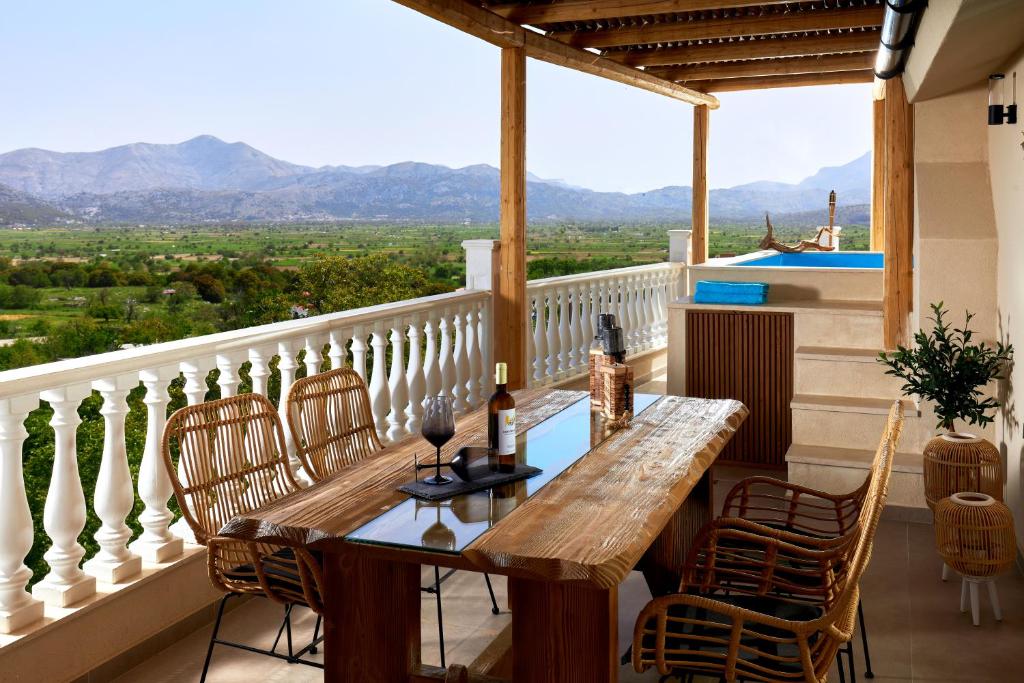 balcón con mesa de madera, sillas y vistas. en Mylostassi Villas with Heated Outdoor Pool, 