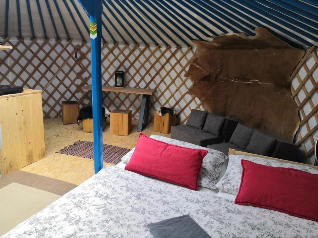 1 cama con 2 almohadas rojas en una yurta en Jurta na zvířecí farmě 