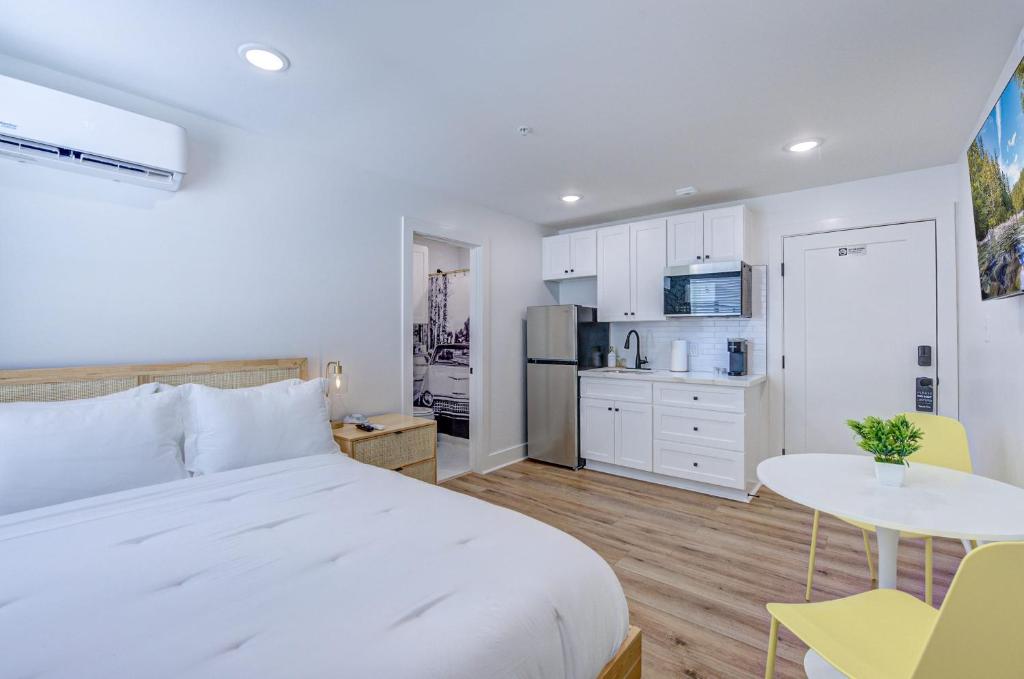 a bedroom with a white bed and a kitchen at Palm Springs Studio Apartment in Galveston