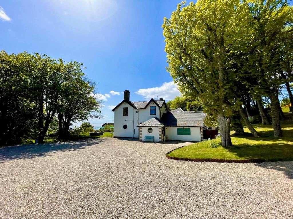 a white house with a tree and a driveway at Navidale House - Bed, Breakfast & Bar in Helmsdale