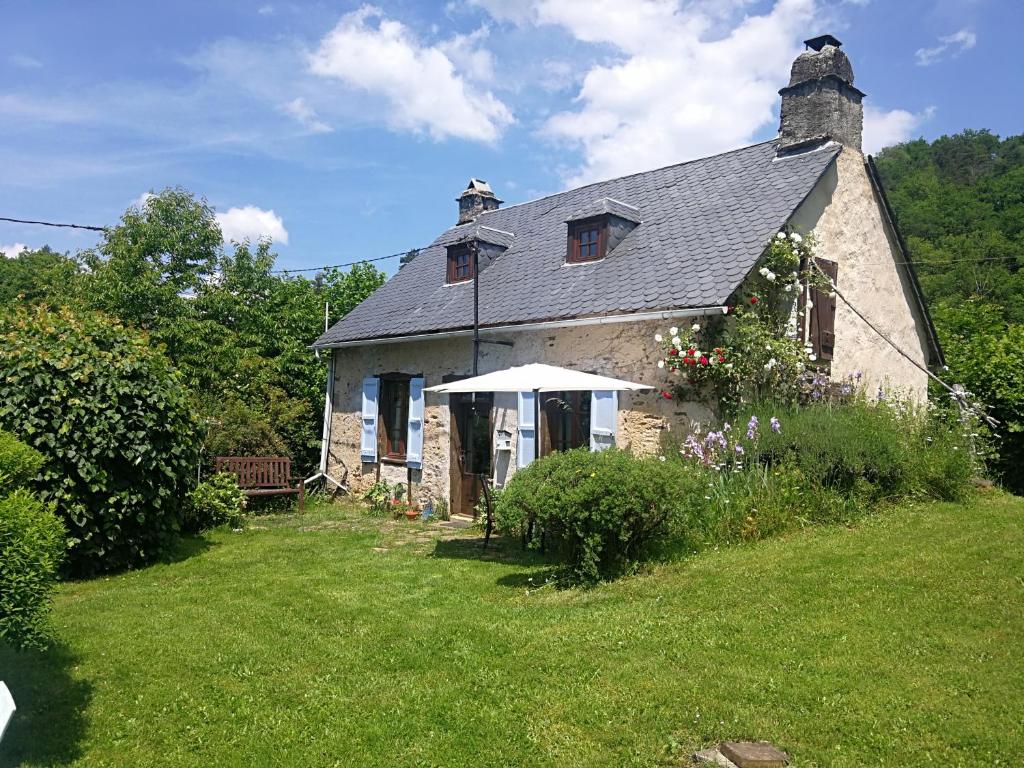 an old stone house with an umbrella in a yard at La Petite Maison Pont Blanchard, in Pléaux