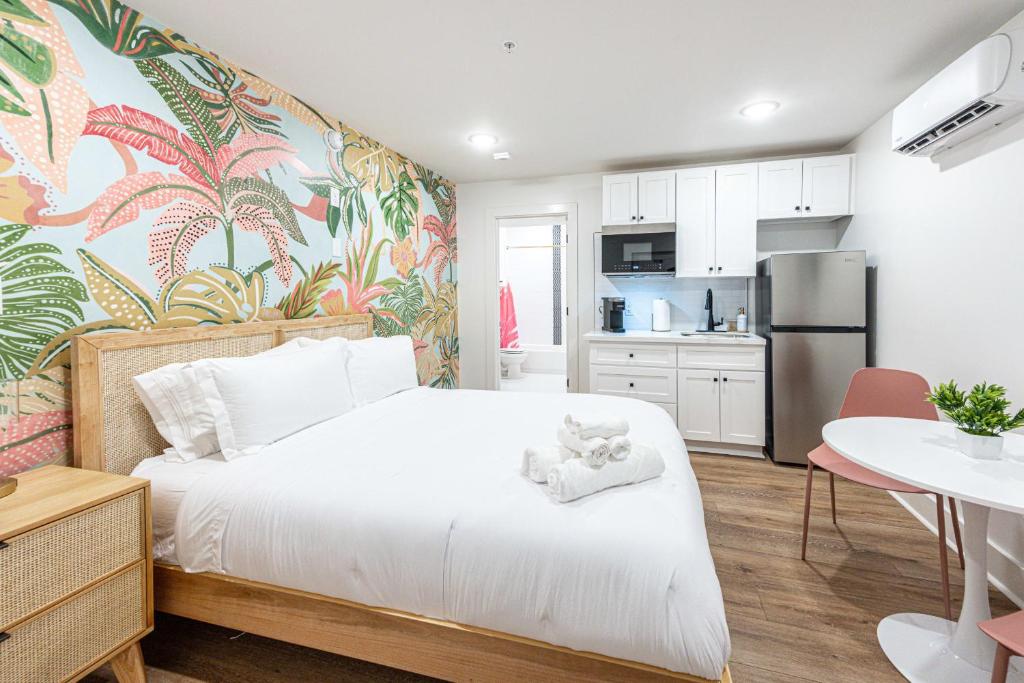a bedroom with a white bed and a kitchen at Pastel Tropics Studio Apartment in Galveston