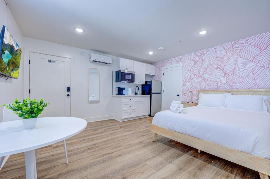 Pink Flamingo Studio Apartment في جالفيستون: غرفة نوم بسرير ابيض وطاولة