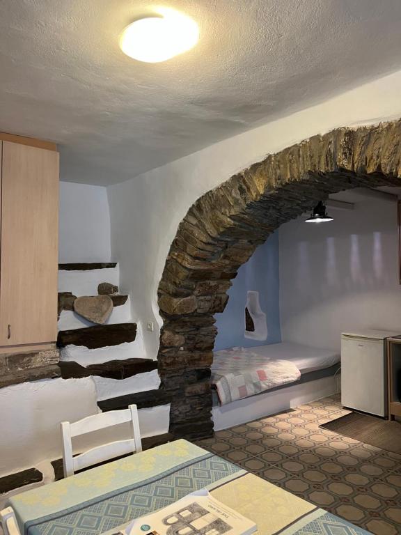a room with a stone wall with a table and chairs at Cellar Falatados in Mési